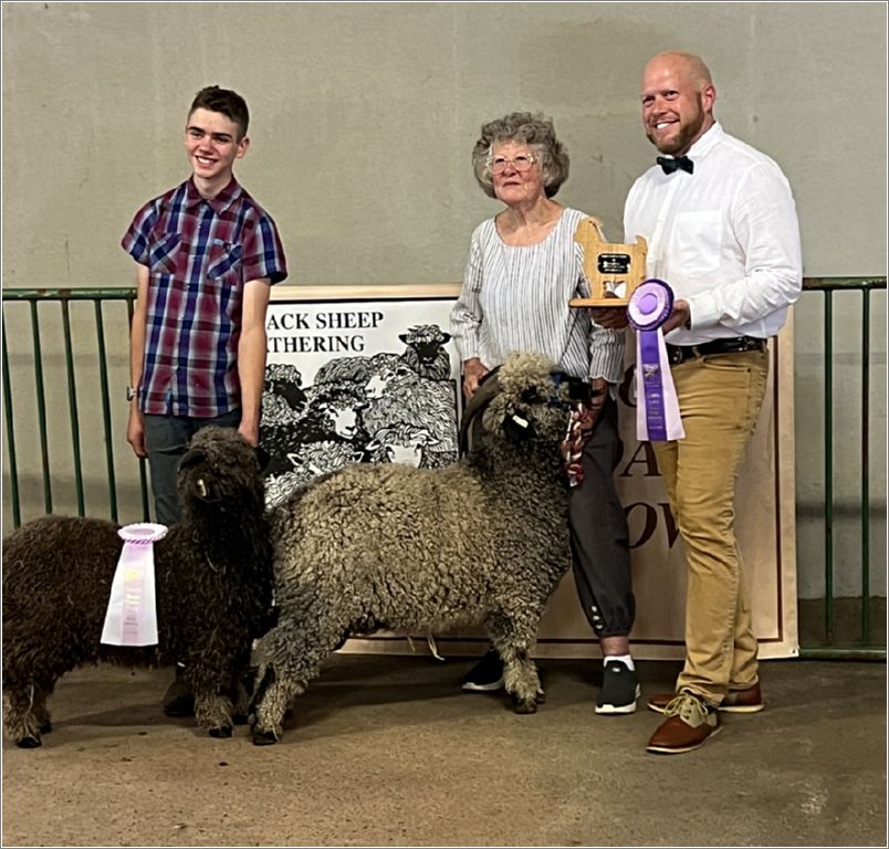 Judge Stewart holds awards while Abram and Carol hold their Champion Colored Buck, Zempire, and Reserve Champion, Chaco, of Ronan Country Fibers. Photo: Sharon Chestnutt.
